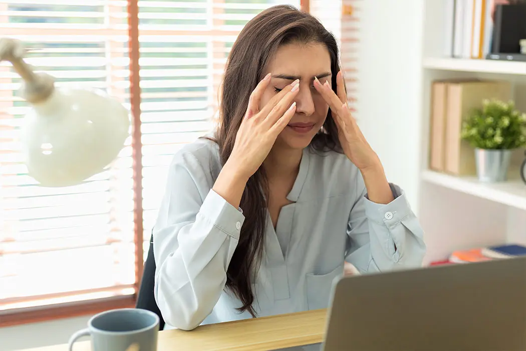 Caregiver with head between hands who is stressed from caregiver burnout