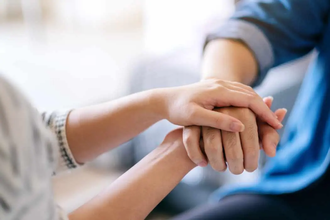 Nurse holding hospice patient hands during one of the levels of hospice care.