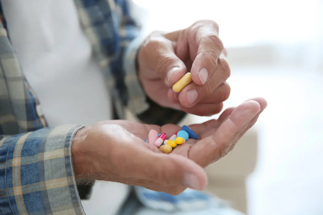 Elderly man holding pills after learning about medication management for seniors in El Paso