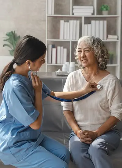 Nurse listening to a senior women's heart.