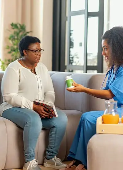 Home nurse going over medications with lady while sitting on the couch