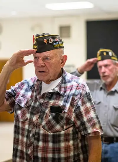 Two elderly veterans saluting at learning event for veterans hospice care