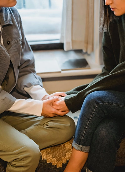 Close up of two people holding hands as they talk about hospice care