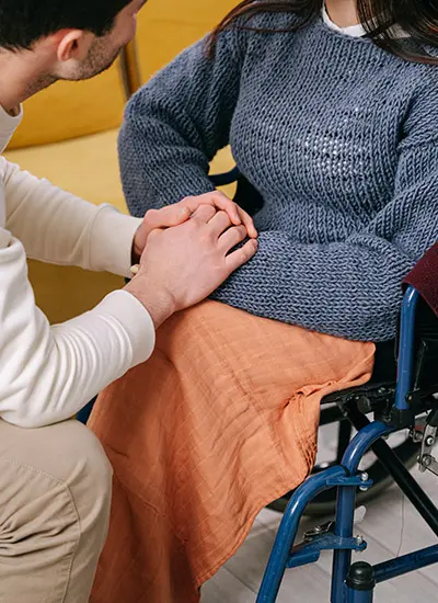 Person holding the hands of another in a wheelchair while getting holistic care